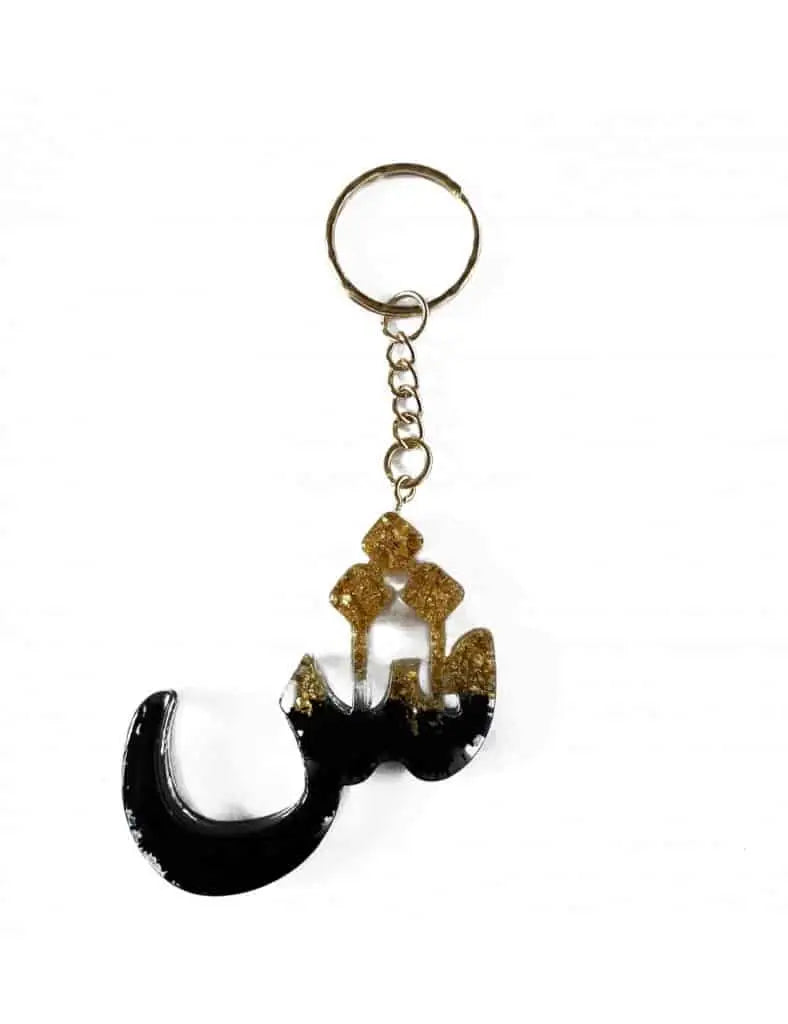 Zwart en gouden resin sleutelhanger in de vorm van de arabische letter ج met metalen ring en ketting van Shien