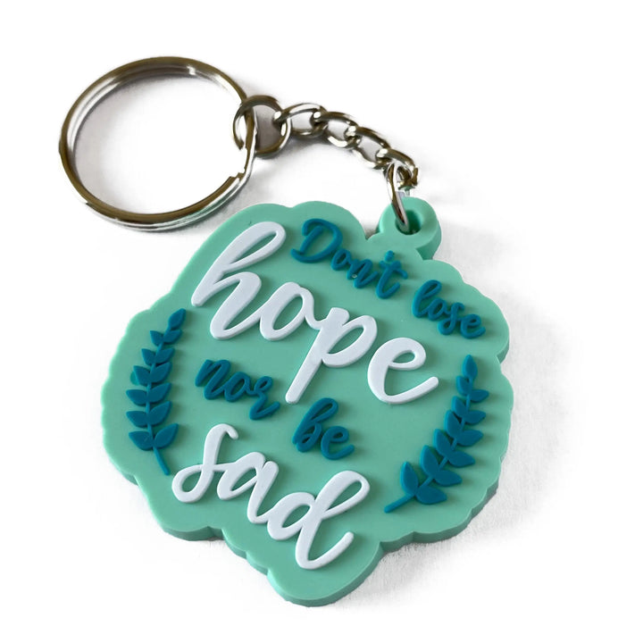 Teal sleutelhanger met geschulpte bladrand en de tekst dont lose hope nor be sad in witte cursieve letters