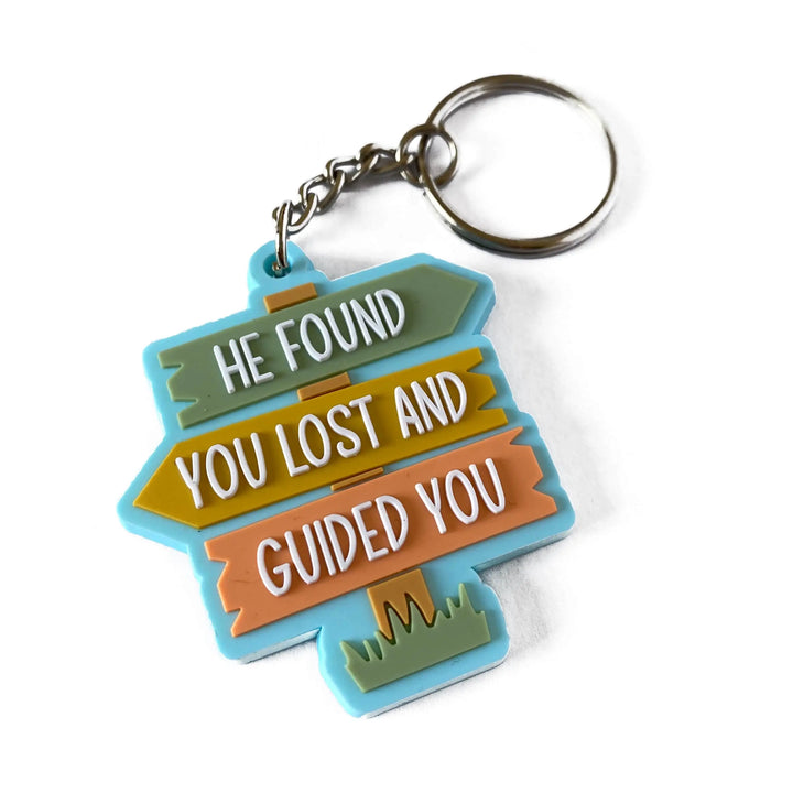 Sleutelhanger van kleurrubbers met drie pijlen en de tekst he found you lost and guided you in wit op groen geel en oranje