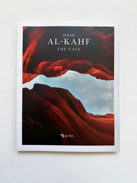 Een hardcover boek met een opvallende roodblauwe kloof landschap cover getiteld surah al-kahf the cave door quwa