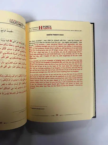 Open book from the explanation of imam al-nawawis 40 hadith 2 volume set with arabic and english text in red on cream pages