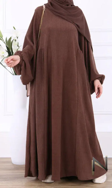 Een vloeiende bruine velvet papillon abaya met ribbelstructuur en lange mouwen, gedragen met bijpassende hijab
