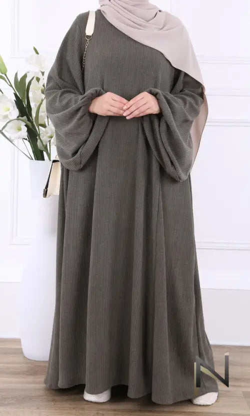 Een vloeiende olivegroene ribgebreide velvet papillon abaya met wijde gedrapeerde mouwen en een bijpassende beige hijab